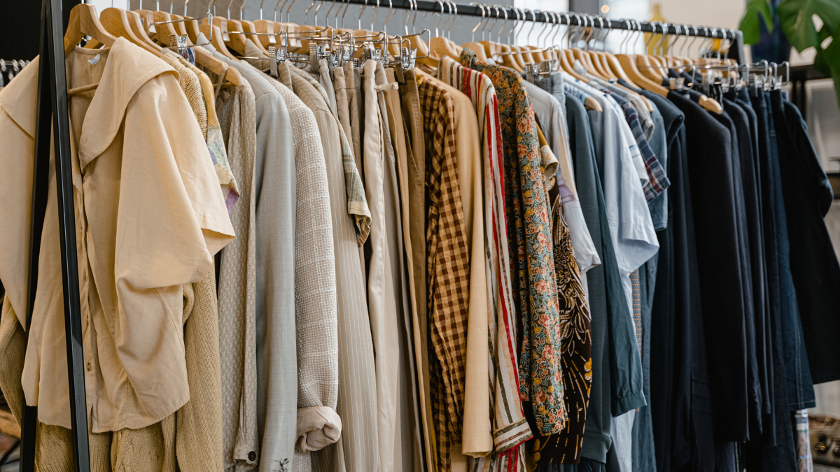 A variety of clothes in different styles, colours, and patterns hang neatly on a rack, showcasing a diverse and colourful wardrobe.